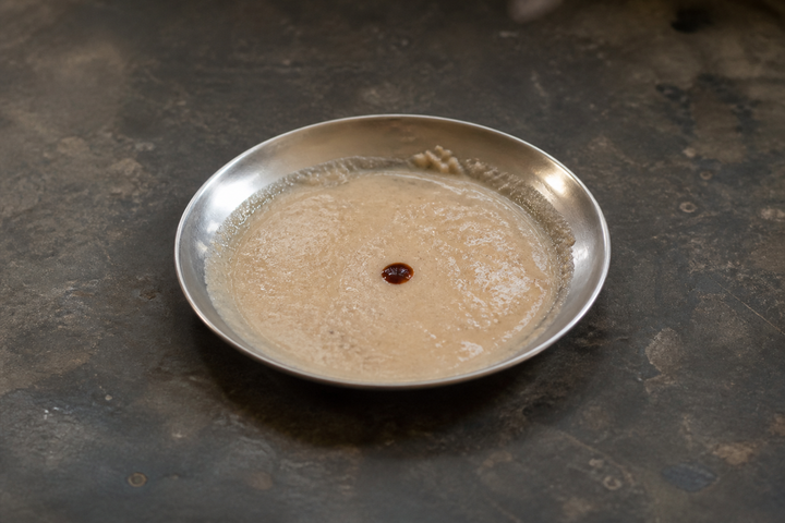 GetPured amchur powder mixed to a pale beige paste in a steel dish with a drop of iodine on it that has not turned blue-black, the at-home starch test